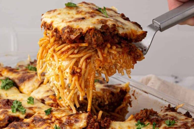 A spatula lifting a slice of Million Dollar Spaghetti from the casserole dish