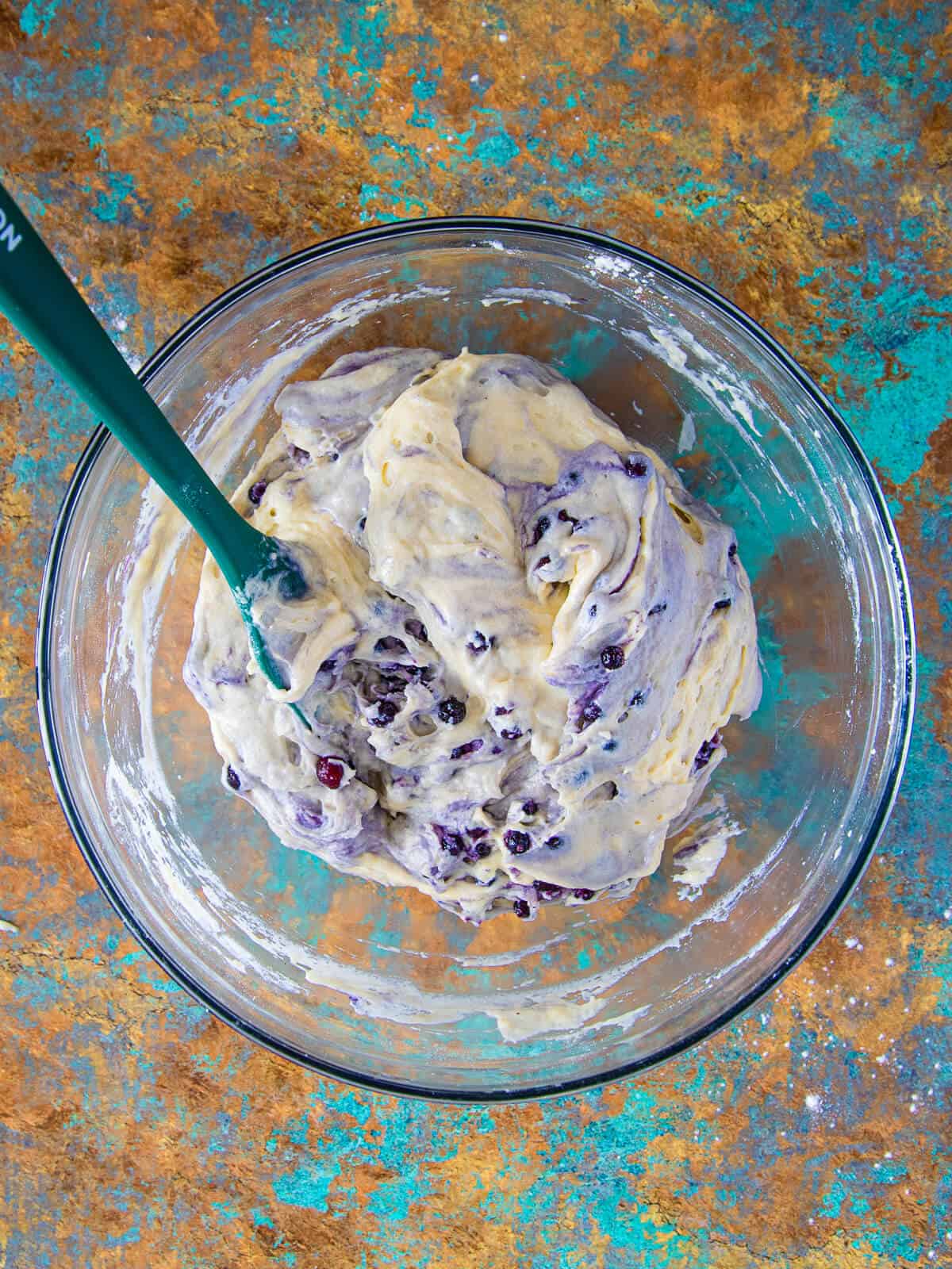 The fresh blueberries are stirred into the batter, giving it a swirled, marbled effect.