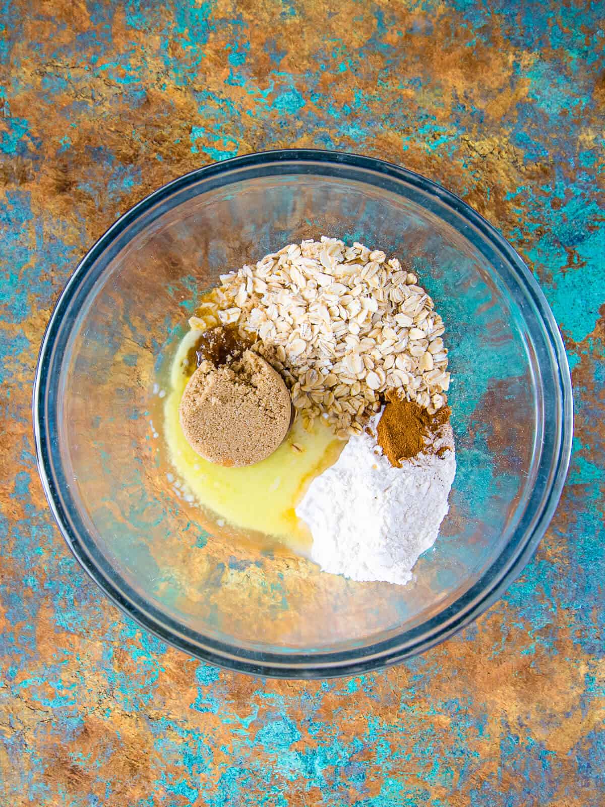 A separate bowl holds brown sugar, oats, flour, melted butter, and cinnamon, ready to be mixed into a crumbly topping.