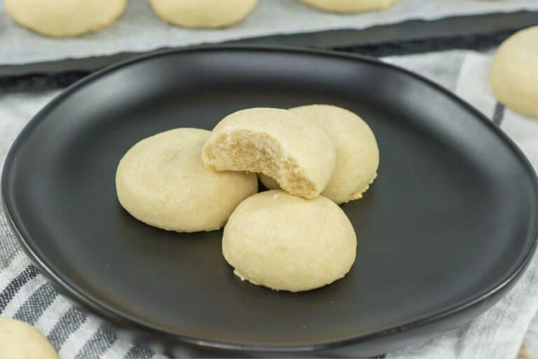 meltaway cookies on a black plate stacked one with a bite taken out of it to show the texture.