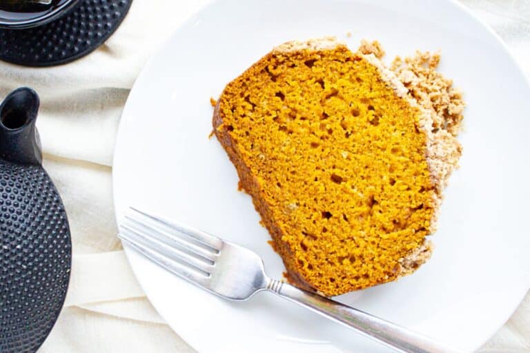 slice of pumpkin bread on a white plate with streusel